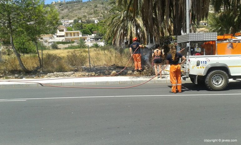 Un miembro de Protección Civil con la manguera apagando el fuego