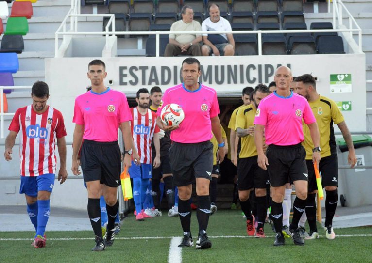 Trío arbitral y equipos saltando al campo