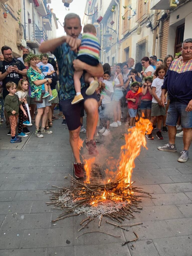 Un padre saltan con su hijo la hoguera infantil