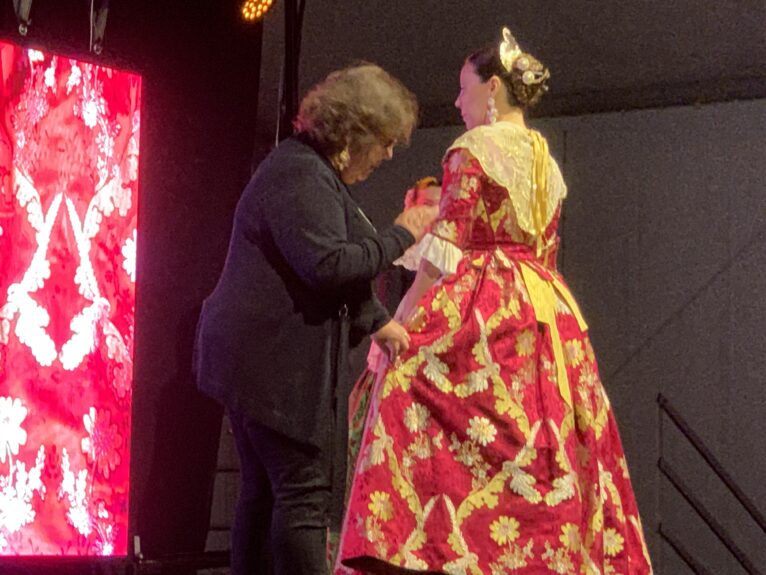 Desfile d'indumentària valenciana Xàbia. Isabel muesta la tela de uno de los trajes