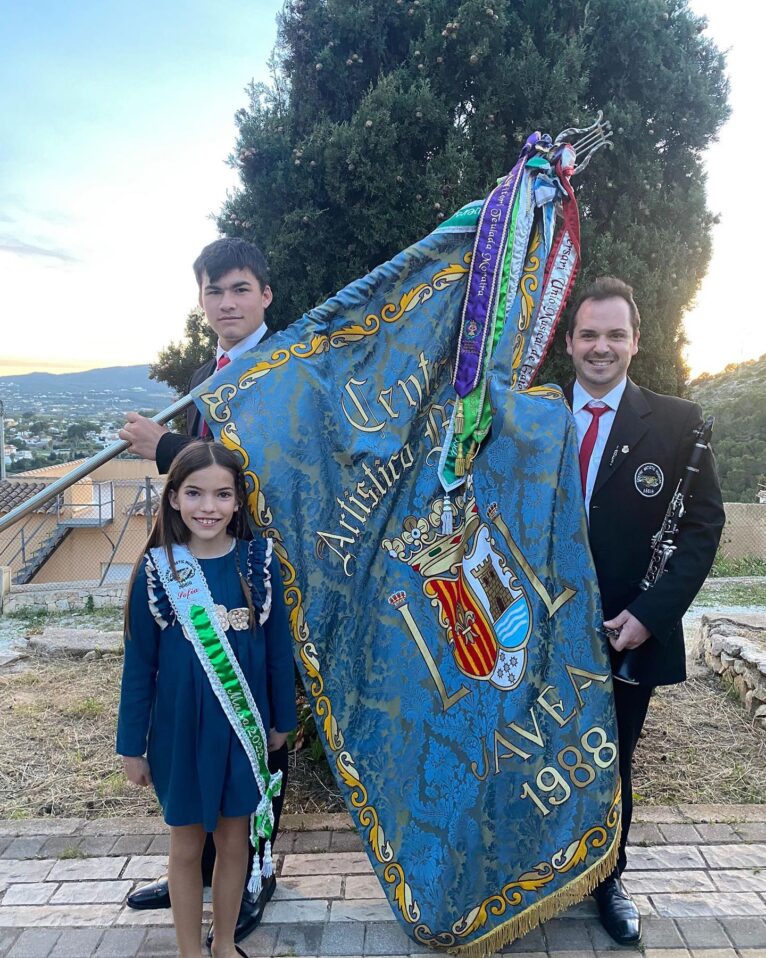 Bandera del Centre Artístic Musical de Xàbia junto al Presidente Juan Antonio Sapena y la musa de 2023 Sofía Chorro