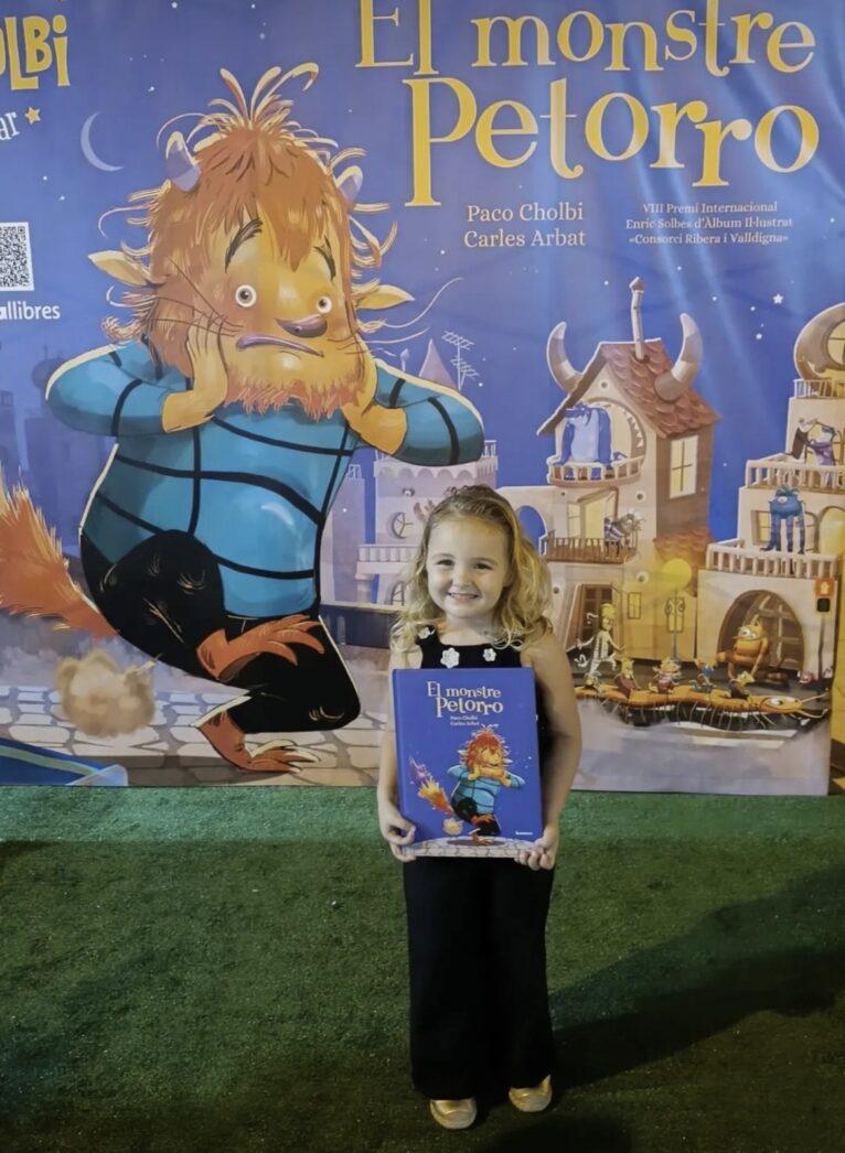 Photocall de El Monstre Petorro. Una niña posa con el cuento firmado