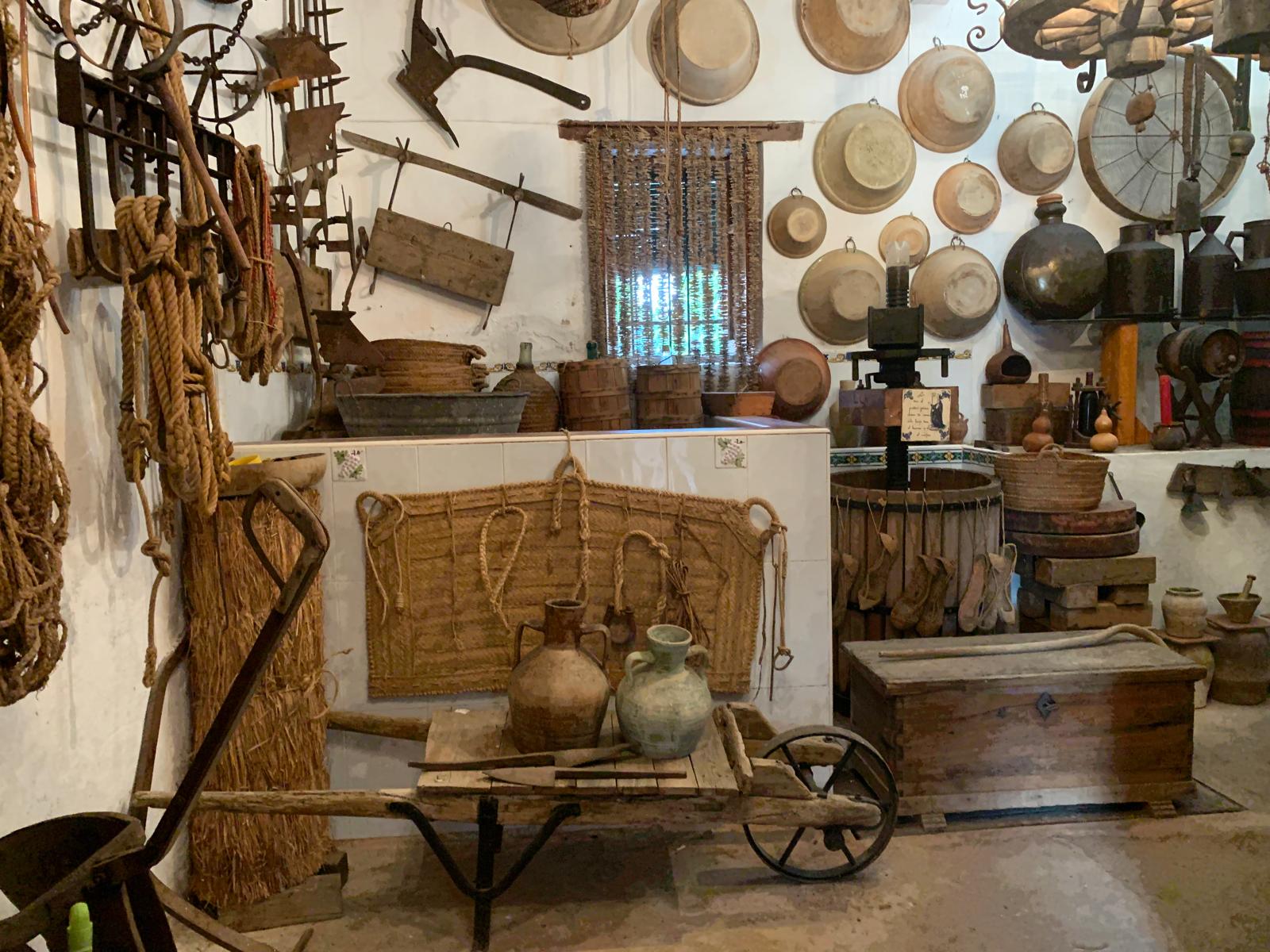 Sala del museo con una antigua carretilla, cántaros e infinidad de enseres de antaño